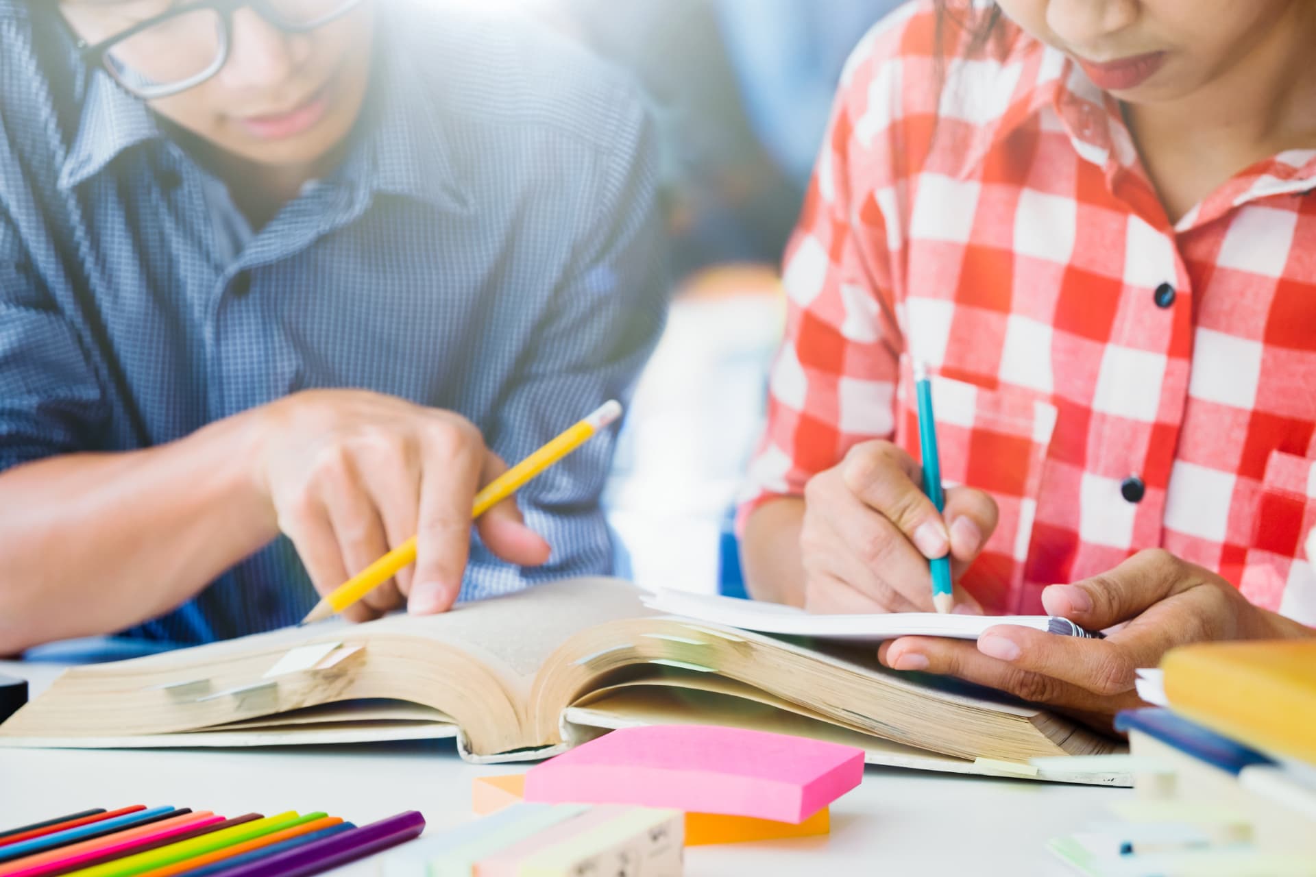 Two students studying together with books and notes